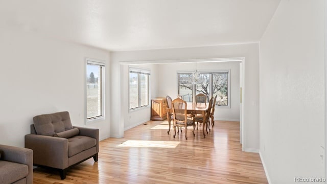 dining room featuring light wood finished floors, an inviting chandelier, and baseboards