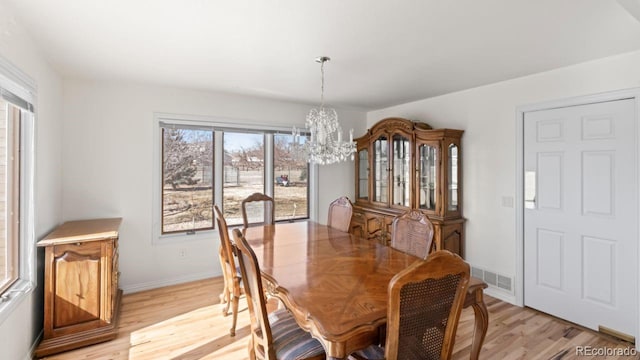 dining space featuring baseboards, light wood-style floors, visible vents, and a notable chandelier