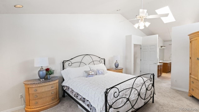 bedroom featuring vaulted ceiling with skylight, baseboards, a ceiling fan, and light colored carpet