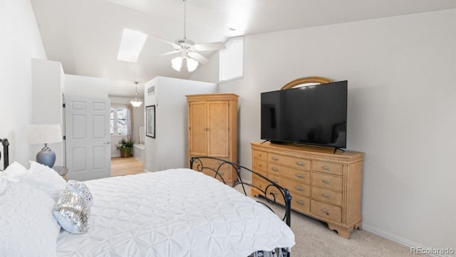 bedroom featuring light carpet, vaulted ceiling with skylight, a ceiling fan, and baseboards