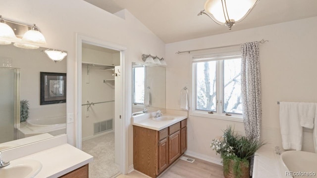 bathroom featuring lofted ceiling, a washtub, a sink, and visible vents