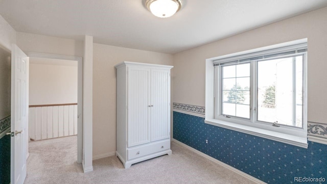 unfurnished bedroom with carpet flooring, baseboards, and wallpapered walls