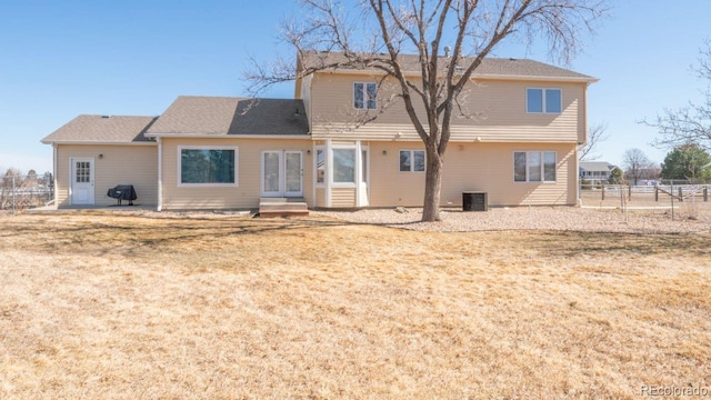 rear view of house featuring entry steps, central AC unit, french doors, fence, and a yard