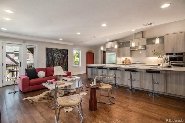 living room featuring plenty of natural light, dark wood-type flooring, lofted ceiling, and sink