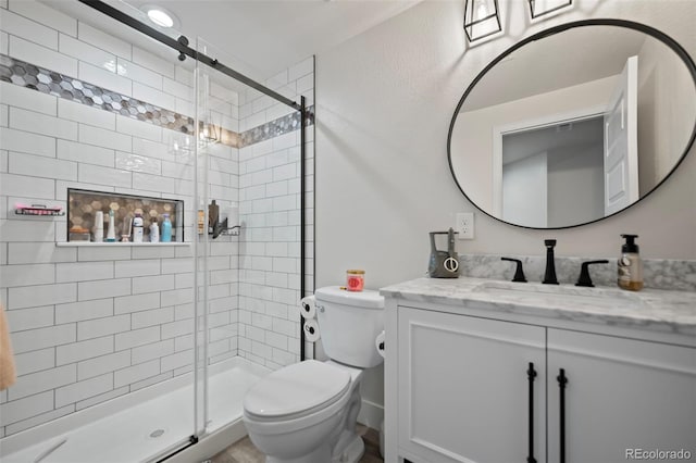 bathroom with toilet, a stall shower, and vanity