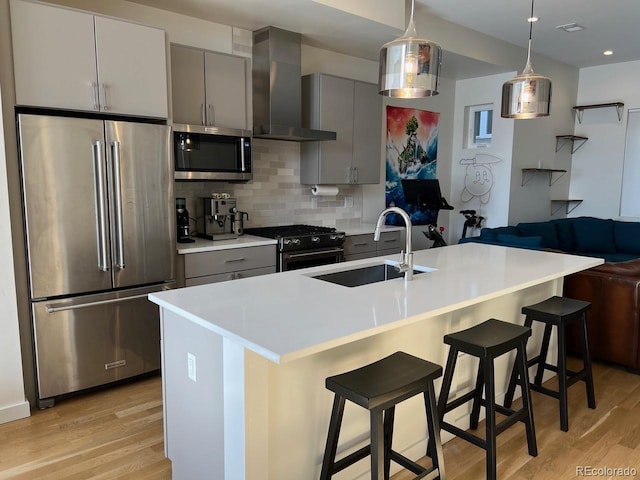 1284 Osceola St, Denver, CO 80204 - kitchen with stainless steel appliances, wall chimney range hood, gray cabinetry, light wood-style flooring, and recessed lighting
