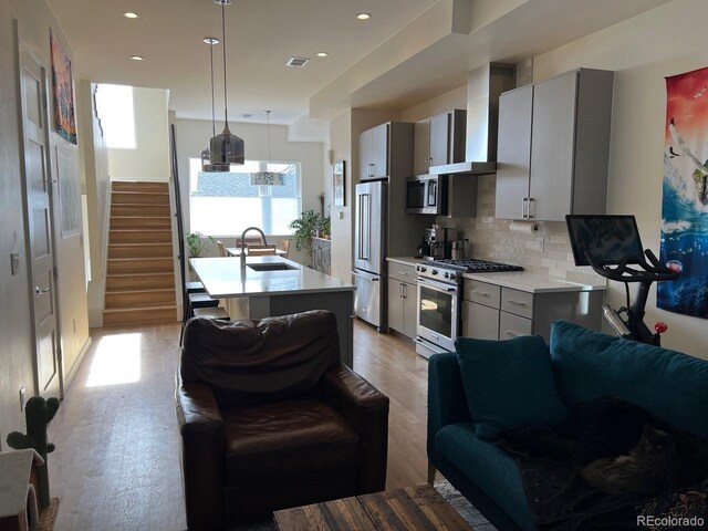 1284 Osceola St, Denver, CO 80204 - kitchen with high quality appliances, wall chimney range hood, light countertops, light wood finished floors, and decorative backsplash