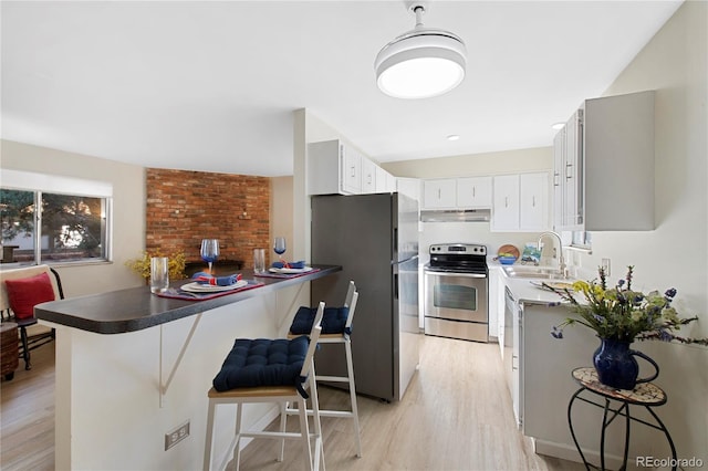 kitchen with sink, kitchen peninsula, stainless steel appliances, and a breakfast bar area