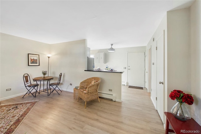 living area with light wood-type flooring and a baseboard heating unit