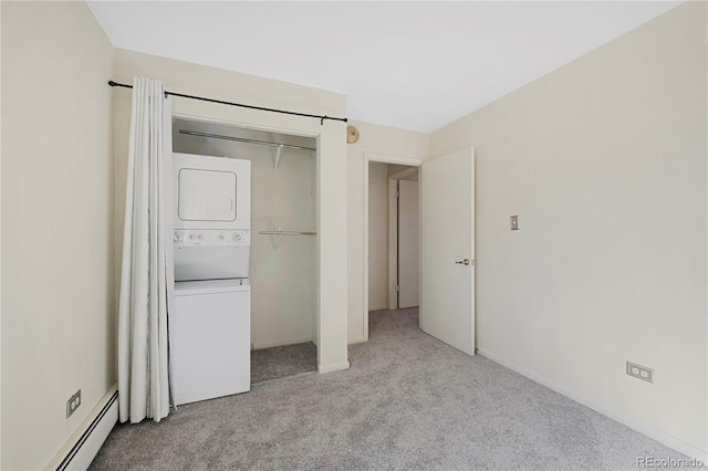 unfurnished bedroom featuring light carpet, a closet, stacked washer and clothes dryer, and a baseboard radiator