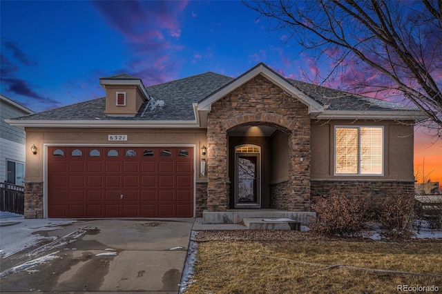 view of front of home with concrete driveway, stone siding, roof with shingles, an attached garage, and stucco siding