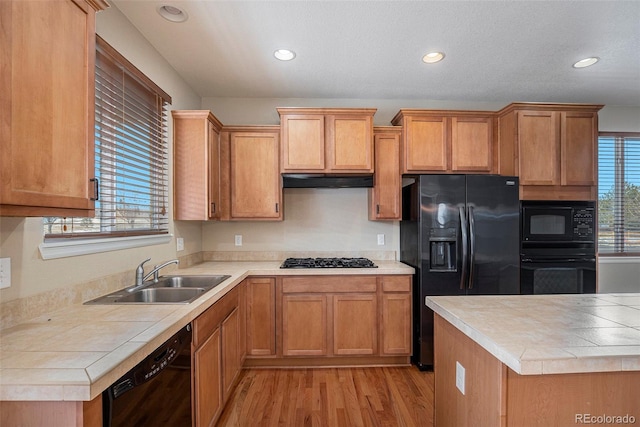 kitchen featuring plenty of natural light, a sink, under cabinet range hood, and black appliances