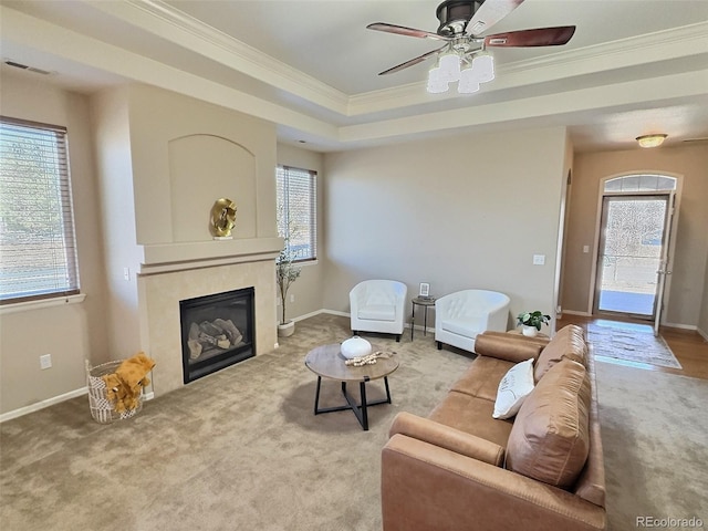 living area featuring baseboards, a tile fireplace, visible vents, and crown molding