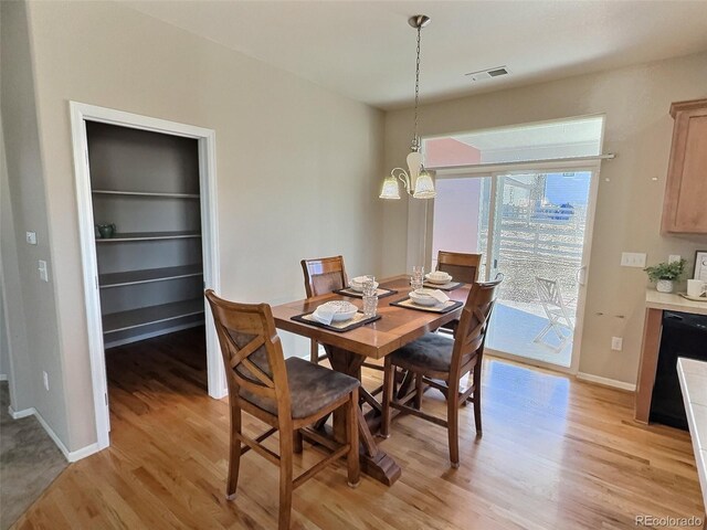 dining room featuring an inviting chandelier, light wood-style flooring, visible vents, and baseboards