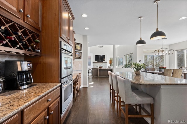 5322 Devils Head Cir, Golden, CO 80403 - kitchen featuring stainless steel double oven, a breakfast bar, light stone countertops, tasteful backsplash, and open floor plan