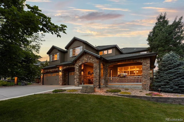 5322 Devils Head Cir, Golden, CO 80403 - view of front of home with stone siding, concrete driveway, an attached garage, covered porch, and a yard