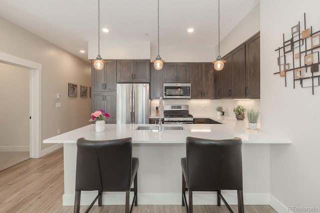 400 Baker Dr Unit Te103, Winter Park, CO 80482 - kitchen with stainless steel appliances, light countertops, a peninsula, dark brown cabinetry, and a breakfast bar area