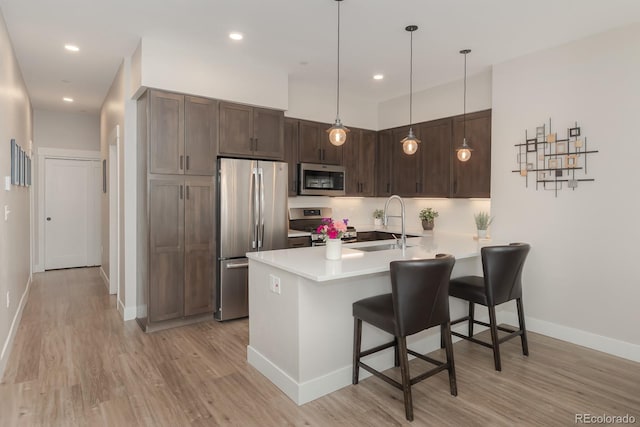 400 Baker Dr Unit Te103, Winter Park, CO 80482 - kitchen with stainless steel appliances, a breakfast bar, a peninsula, light wood-type flooring, and dark brown cabinets