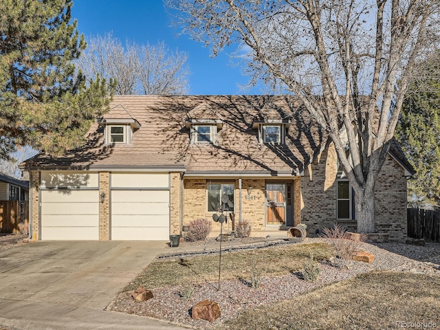 view of front facade with a garage, concrete driveway, brick siding, and fence