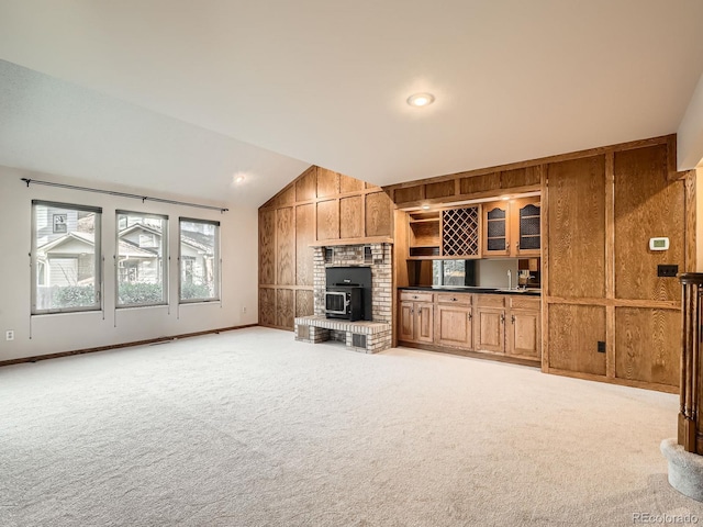 unfurnished living room featuring lofted ceiling, light carpet, and wooden walls