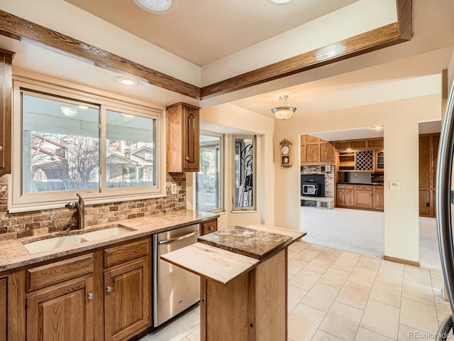 kitchen featuring a kitchen island, tasteful backsplash, dishwasher, sink, and a brick fireplace