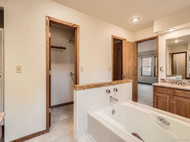 bathroom featuring vanity, a relaxing tiled tub, and tile patterned floors