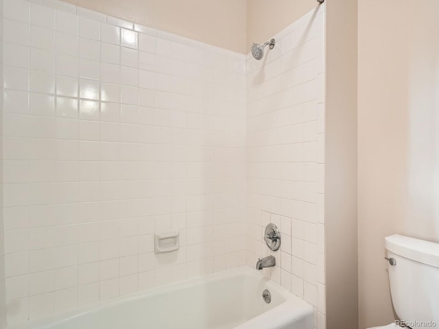 bathroom featuring tiled shower / bath combo and toilet