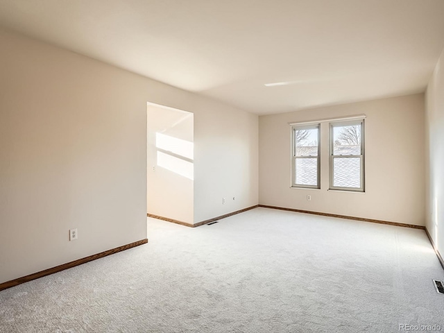 unfurnished room with light carpet and baseboards