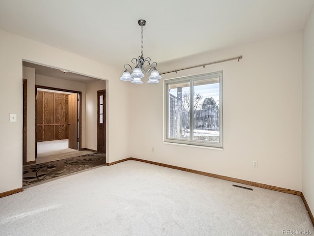 spare room with carpet flooring, a chandelier, and baseboards