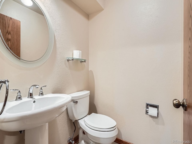 half bathroom featuring toilet and a sink