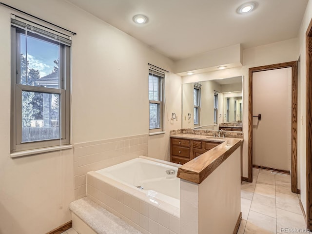 bathroom with a bath, vanity, tile patterned flooring, and recessed lighting