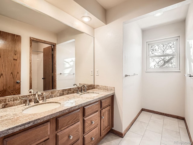 full bath featuring double vanity, baseboards, and tile patterned flooring