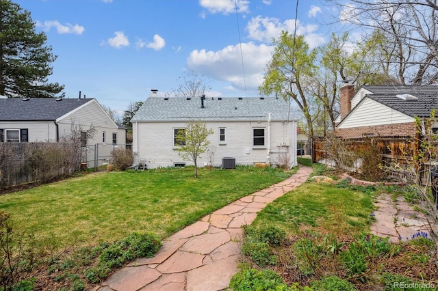 rear view of house featuring central air condition unit, a fenced backyard, and a lawn