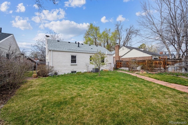 back of house featuring a yard, brick siding, fence, and a chimney