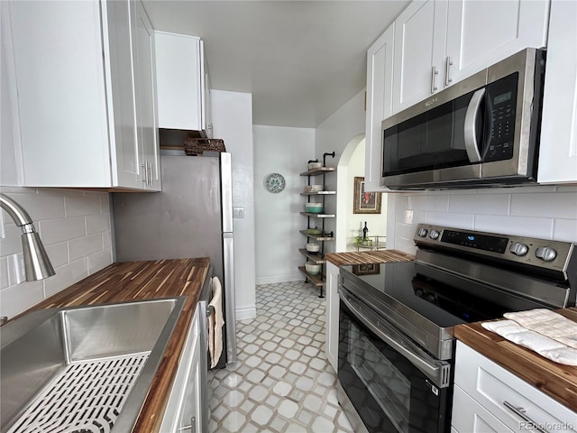 kitchen featuring light floors, wood counters, white cabinetry, and stainless steel appliances