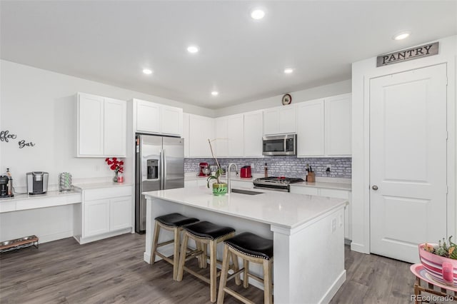17471 Gandy Dancer Ln, Parker, CO 80134 - kitchen featuring appliances with stainless steel finishes, wood finished floors, backsplash, a kitchen bar, and recessed lighting