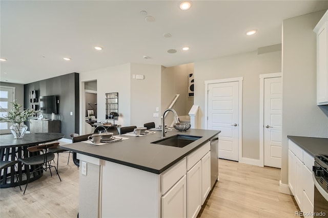 6864 Bryant Ct, Denver, CO 80221 - kitchen with a sink, dark countertops, light wood-type flooring, dishwasher, and recessed lighting
