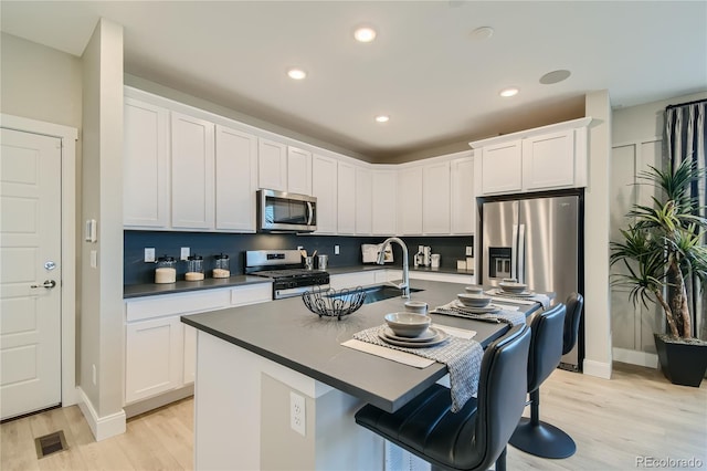 6864 Bryant Ct, Denver, CO 80221 - kitchen with stainless steel appliances, dark countertops, light wood-style flooring, a kitchen bar, and recessed lighting