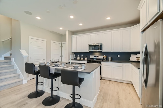 6864 Bryant Ct, Denver, CO 80221 - kitchen with appliances with stainless steel finishes, a sink, dark countertops, light wood-style flooring, and white cabinets
