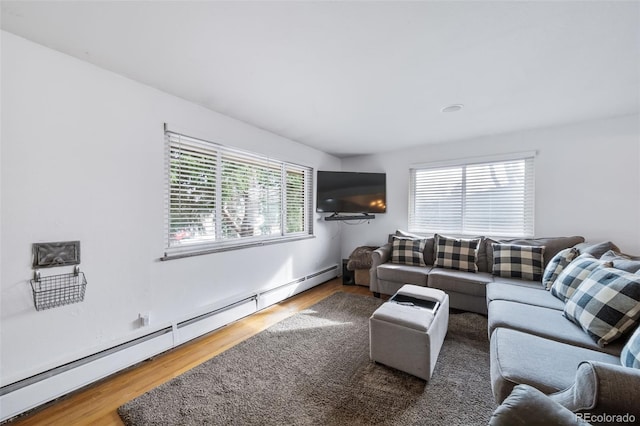 living room with baseboard heating, a healthy amount of sunlight, and hardwood / wood-style flooring