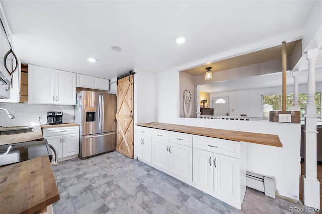 kitchen featuring white cabinetry, kitchen peninsula, stainless steel fridge with ice dispenser, a baseboard radiator, and a barn door