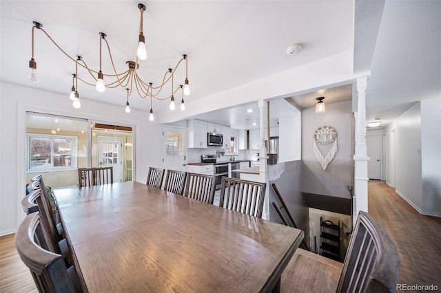 dining space featuring decorative columns and light hardwood / wood-style flooring