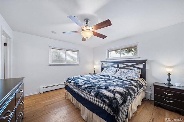 bedroom featuring multiple windows, a baseboard heating unit, light hardwood / wood-style flooring, and ceiling fan