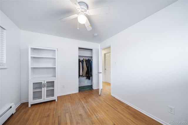 unfurnished bedroom with a baseboard radiator, light hardwood / wood-style floors, a closet, and ceiling fan