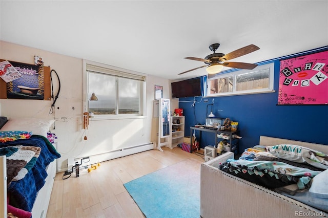 bedroom featuring a baseboard heating unit, hardwood / wood-style floors, and ceiling fan