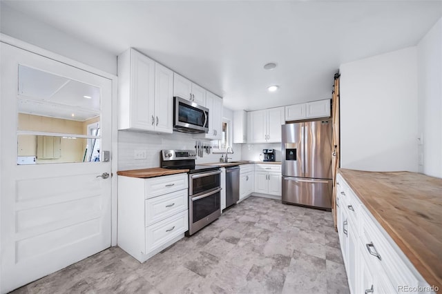 kitchen featuring white cabinetry, appliances with stainless steel finishes, backsplash, and wood counters