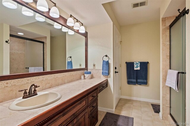 2854 Tenderfoot Hill St, Colorado Springs, CO 80906 - full bathroom featuring visible vents, baseboards, vanity, tile patterned floors, and a stall shower