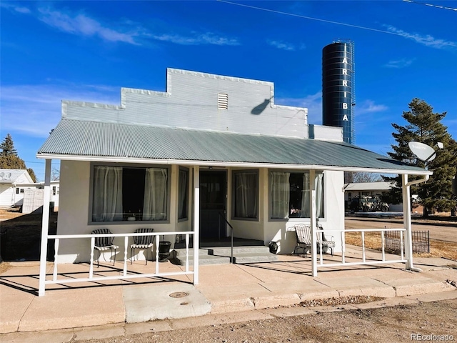 view of front of house with stucco siding, metal roof, and covered porch