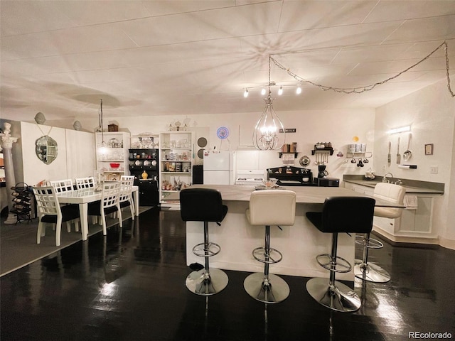 kitchen with dark wood-style flooring, freestanding refrigerator, light countertops, a kitchen island, and a breakfast bar area