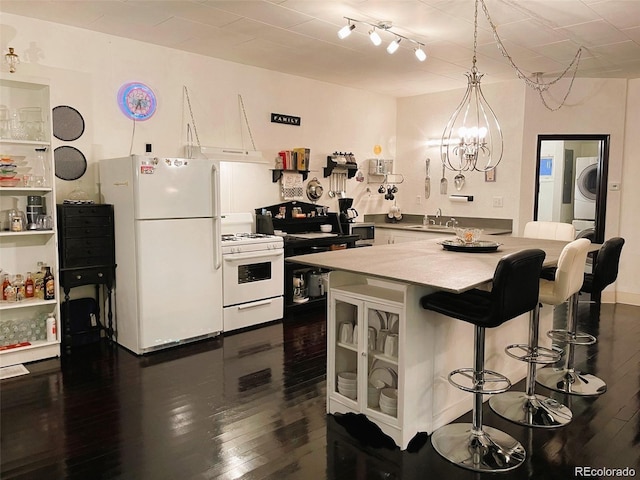 kitchen with a sink, a notable chandelier, white appliances, washer / clothes dryer, and dark wood-type flooring